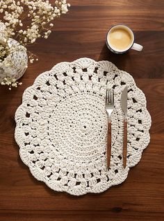 a crocheted placemat with two forks and a cup of coffee