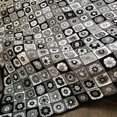 a black and white quilt on top of a wooden floor