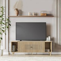 a flat screen tv sitting on top of a wooden entertainment center next to a potted plant