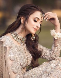 a beautiful woman in a white dress with long hair and jewelry on her head, posing for