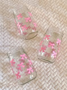 three glass jars with pink and white stars in them sitting on a toweled surface