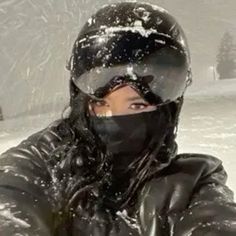 a woman wearing a helmet and covering her face in the snow