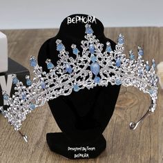 a tiara with blue and white stones on it sitting on a black display stand