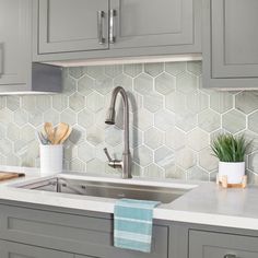 a kitchen with gray cabinets and white counter tops, wooden utensils on the sink