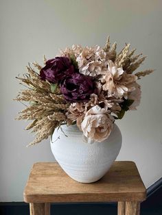 a white vase filled with flowers on top of a wooden table