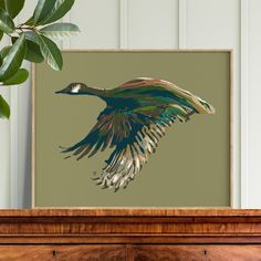 a painting of a bird flying in the air on a wall above a wooden dresser