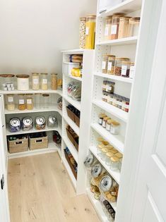 an organized pantry with white shelving and wooden floors