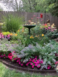 a bird bath surrounded by colorful flowers in a garden