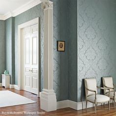 a room with blue walls and white trim, two chairs in front of the door