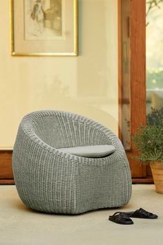 a grey chair sitting on top of a floor next to a potted plant