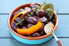 a bowl filled with olives and orange peels on top of a wooden table