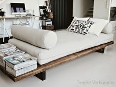 a white couch with pillows on it in front of a desk and bookshelf