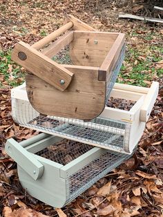 a wooden birdcage sitting on top of a pile of leaves