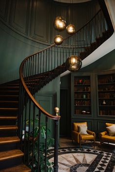 a spiral staircase in the middle of a room with two chairs and a rug on the floor