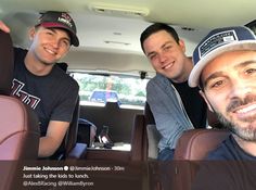 three men sitting in the back seat of a car with one man wearing a hat