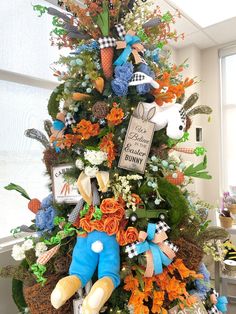 a decorated christmas tree in an office cubicle with stuffed animals and flowers on it