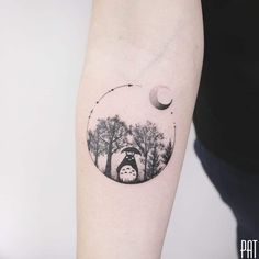 a woman's arm with a tattoo on it that has an image of the moon and trees