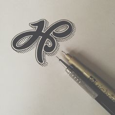 a pen is sitting on top of a piece of paper with the letter k in it