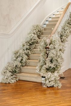 the stairs are decorated with white flowers and greenery for an elegant touch to any room