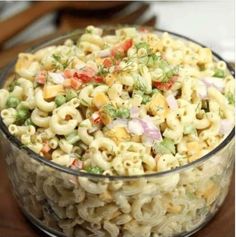 a bowl filled with macaroni salad on top of a wooden table