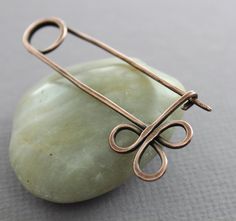 a piece of metal sitting on top of a green rock next to a pin with scissors in it