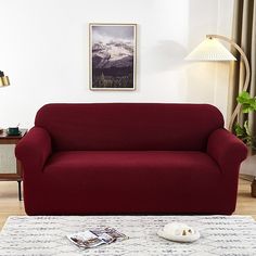 a red couch sitting on top of a white rug in a living room next to a lamp