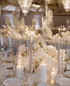 the table is set with white flowers and candles for an elegant wedding reception or special event