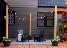 two chairs sitting on top of a wooden deck next to a planter filled with potted plants