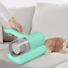 a cat laying on top of a couch next to a person using a vacuum cleaner