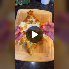 a person holding a piece of pizza on top of a wooden cutting board