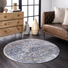 a living room with a couch, chair and round rug on the floor in front of a window