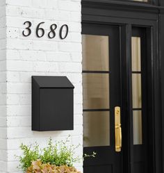 a black mailbox mounted to the side of a white brick building