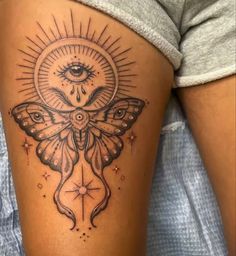 a woman's thigh with a moth tattoo on it and an all seeing eye