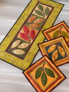 three quilted placemats with leaf designs on them