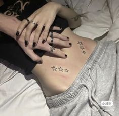 a woman laying on top of a bed with her stomach covered in stars and tattoos