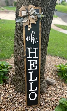 a sign that says hello hanging on a tree