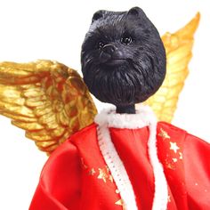 a small black dog wearing a red coat and gold wings