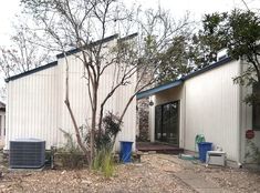 an outside view of a house with trees and trash cans