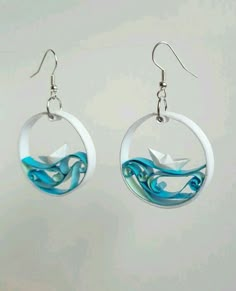 the earrings are decorated with blue swirls and white paper cranes on them, as well as an origami bird