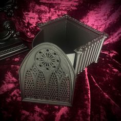 an ornate metal box sits on a velvet surface