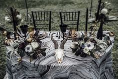 a table topped with black chairs covered in animal skulls and flowers on top of it