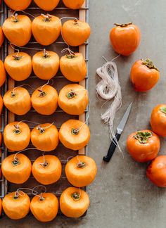 several orange tomatoes are sitting on a rack next to a pair of scissors and twine