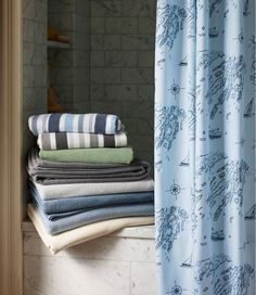 towels stacked on top of each other in front of a shower curtain with blue and white designs