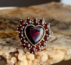 An old stock antique Victorian bohemian garnet ring set in 14k gold. In immaculate condition.  A dear heart ring set in garnet symbolizes passion and love. They are usually given to their sweetheart. Natural rose cut garnets. 14K solid gold. Size 6 and easily sizable by your local jeweler.   Open back Garnet Heart Ring, Vintage Gemstone Rings For Valentine's Day, Vintage Heart Ring With Birthstone, Vintage Birthstone Rings For Valentine's Day, Vintage Heart Ring With Birthstone For Valentine's Day, Vintage Ruby Ring For Valentine's Day Anniversary, Vintage Ruby Ring For Anniversary On Valentine's Day, Heart Rings, Victorian Wedding Ring