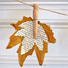 an ornament made out of book pages hanging from a string with a wooden stick