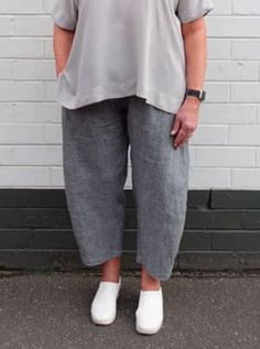 a woman standing in front of a white brick wall with her hands on her hips