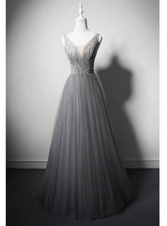 Anchored in timeless elegance and contemporary design, this grey prom dress is designed to captivate. The deep V-neckline adds a touch of allure, while the intricately beaded bodice creates a stunning focal point that shimmers beautifully. The tulle skirt flows gracefully to the floor, creating a classic A-line silhouette that is both flattering and enchanting. Made from premium materials, this dress promises comfort and style, allowing you to move with ease and confidence throughout the evening. Ideal for prom, formal events, or any special occasion, this dress combines sophistication and modernity effortlessly. Complete your ensemble with delicate accessories and a pair of stylish heels to ensure you shine throughout the night. Grey Evening Dresses, Grey Prom Dress, Blue Ball Gowns, Fashion Week Outfit, Green Tulle, Trendy Plus Size Fashion, Sequin Prom Dress, Quinceanera Dress, Beaded Prom Dress