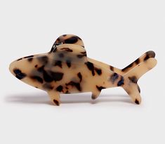 a small plastic toy fish on a white surface with black spots and brown spots around it's body