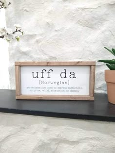 a potted plant sitting on top of a shelf next to a sign that says uff da