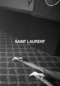 a woman laying on top of a bed next to a wall with the words saint laurent